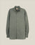 A long-sleeve button-down shirt in a muted sage green color, featuring a chest pocket and silver-toned buttons, displayed against a solid light beige background.  Made in USA Oxford Cloth Button Down shirt.