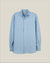 A light blue long-sleeve button-down shirt with a chest pocket, displayed flat against a solid beige background.  Made in USA OCBD shirt.  